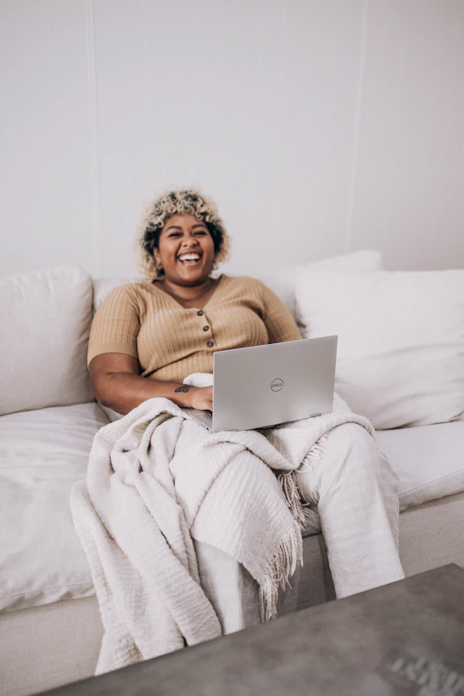 Woman in a brown sweater sitting comfortably on a white couch