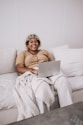 woman in brown sweater sitting on white couch