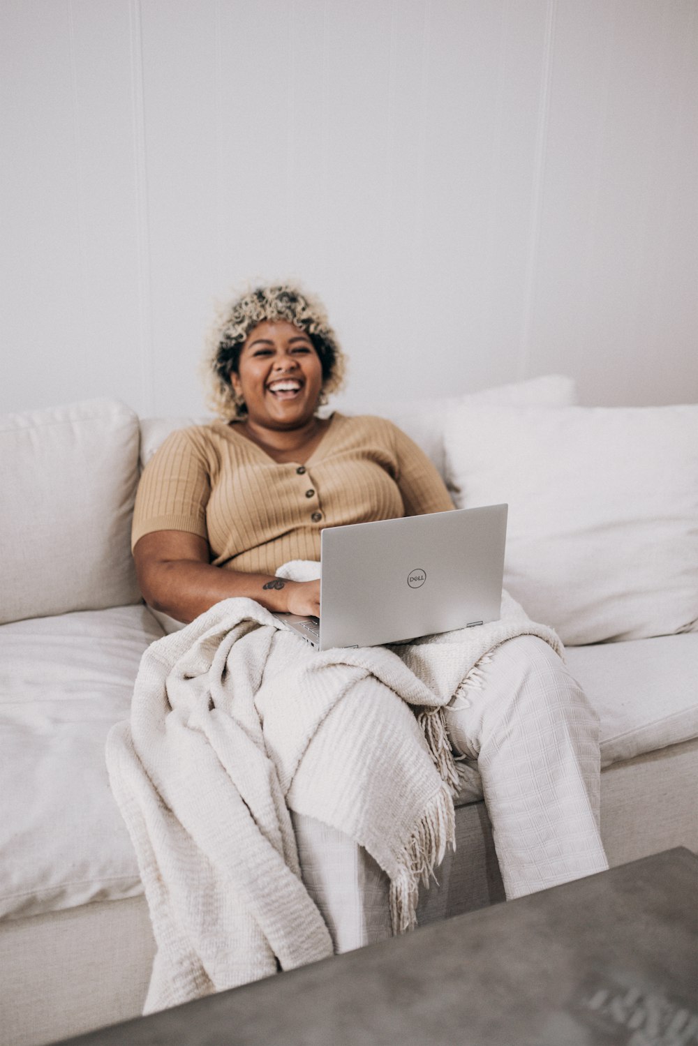 Frau im braunen Pullover sitzt auf weißer Couch