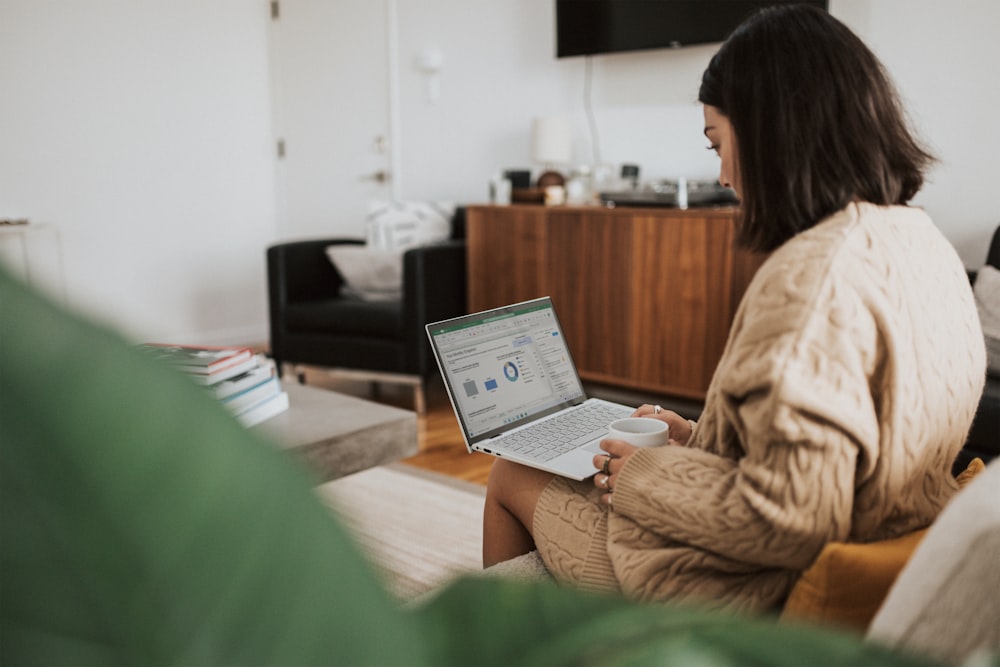 woman in brown jacket sitting on chair using laptop