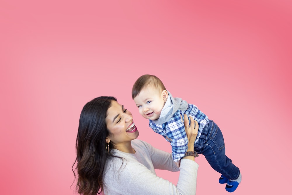 woman in white long sleeve shirt carrying baby in blue and white plaid dress shirt