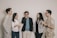 A diverse group of people smiling and sharing positive feedback in a casual meeting setting.