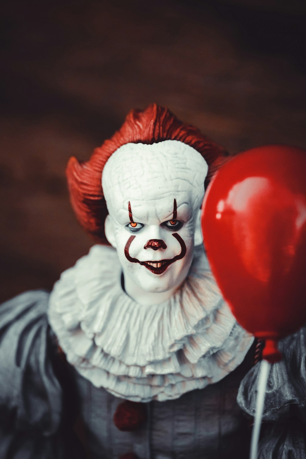 white and red clown holding heart balloon