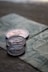 Three coins are placed on top of a paper currency with intricate designs. The focus is on the coins, which appear to have an embossed profile of a person and include engraved text.