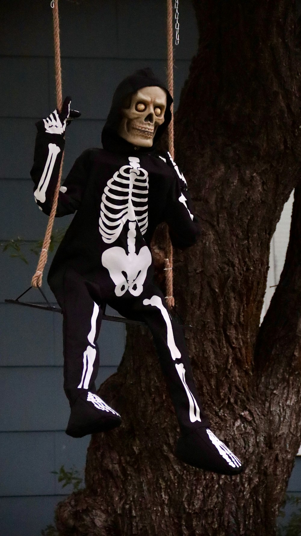 man in black and white skeleton costume standing beside brown tree