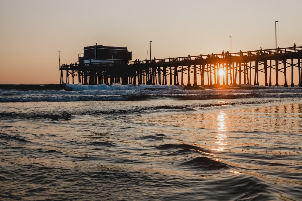 silhouette of dock on sea during sunset