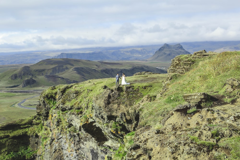 man and woman standing on green grass covered hill during daytime