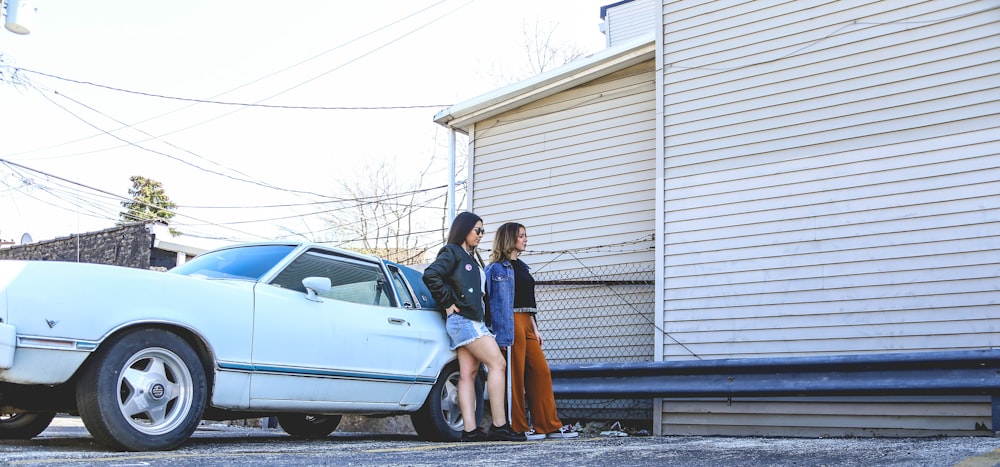 man and woman standing beside white car