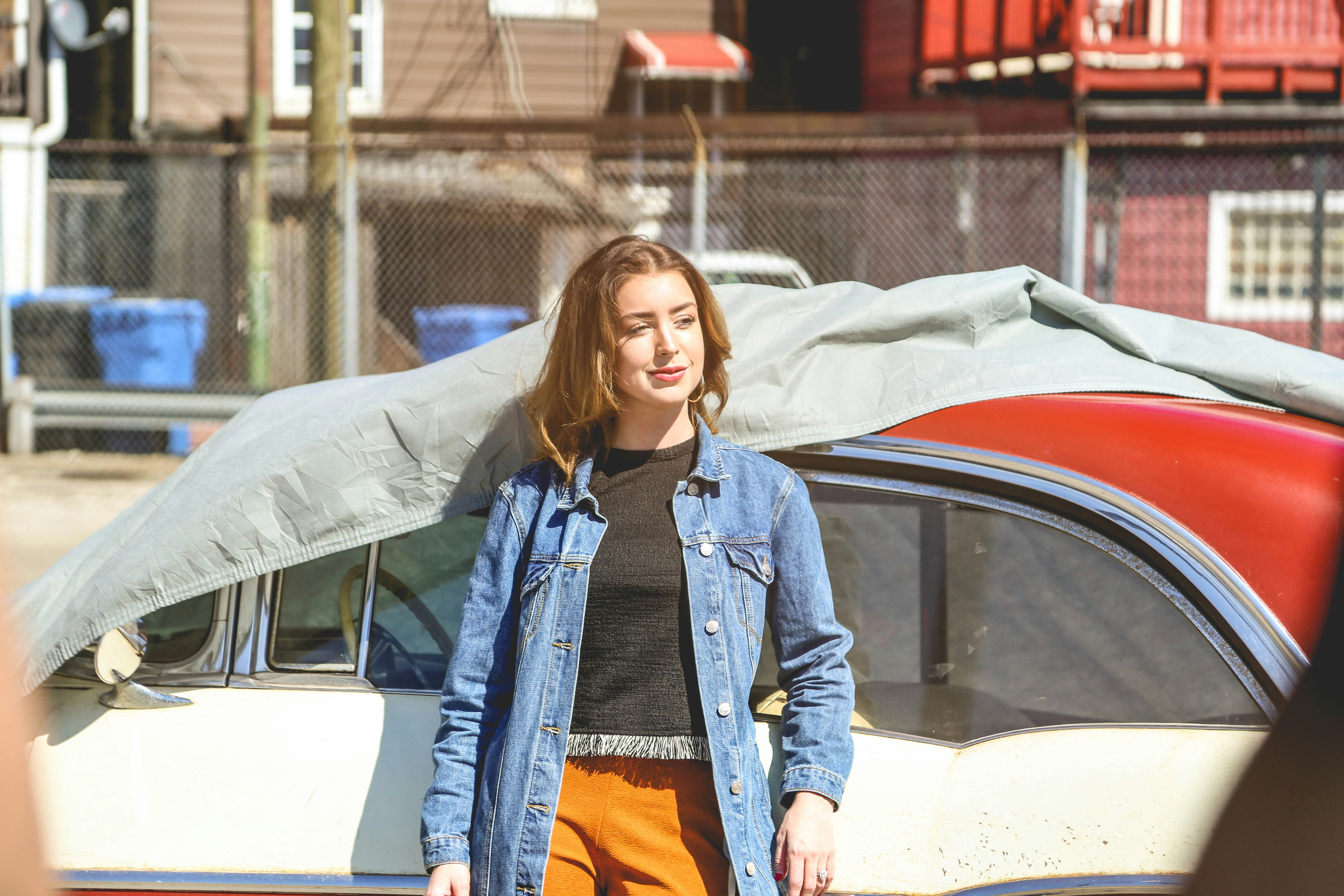 woman in blue denim jacket standing beside white car, Woman posing in front of a car in Pilsen in Chicago.
