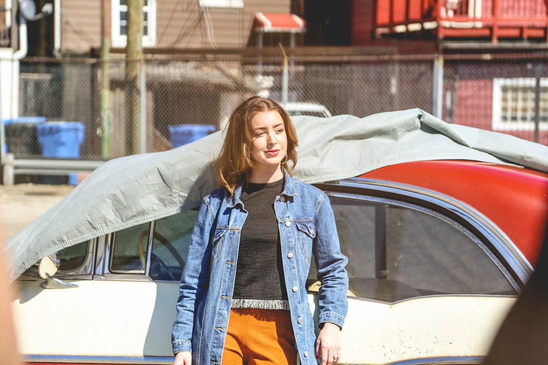 woman in blue denim jacket standing beside white car, Woman posing in front of a car in Pilsen in Chicago.