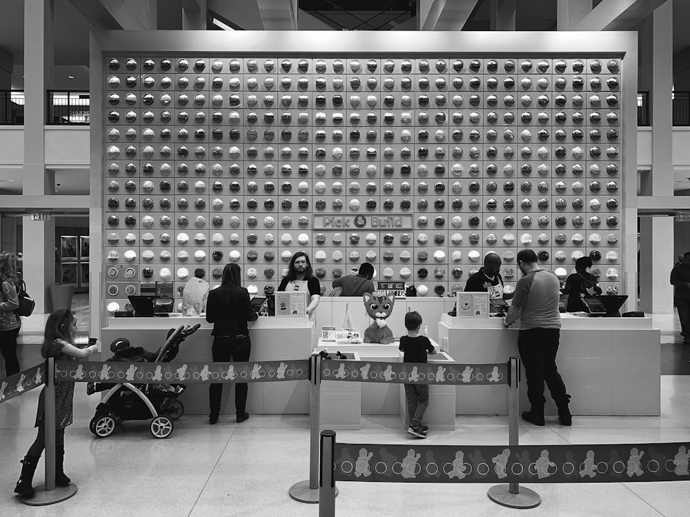 grayscale photo of people standing in front of table