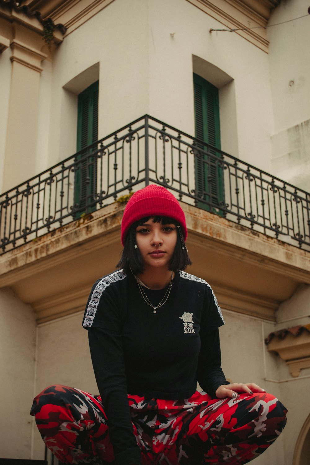 woman in black and white long sleeve shirt and red knit cap standing near yellow concrete