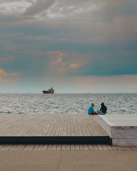 man and woman sitting on dock during daytime in Thessaloniki Greece