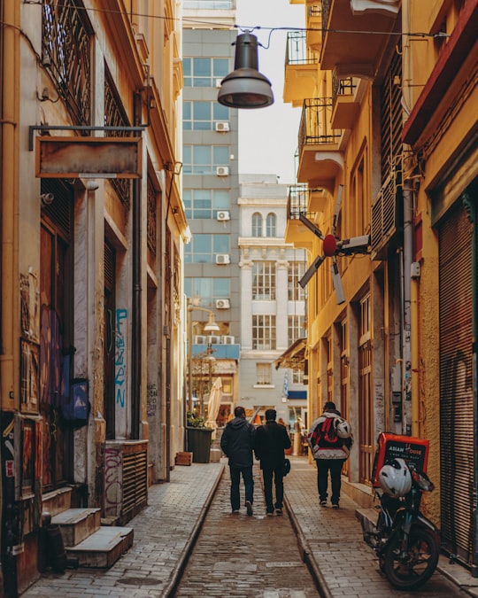 people walking on sidewalk between buildings during daytime in Thessaloniki Greece