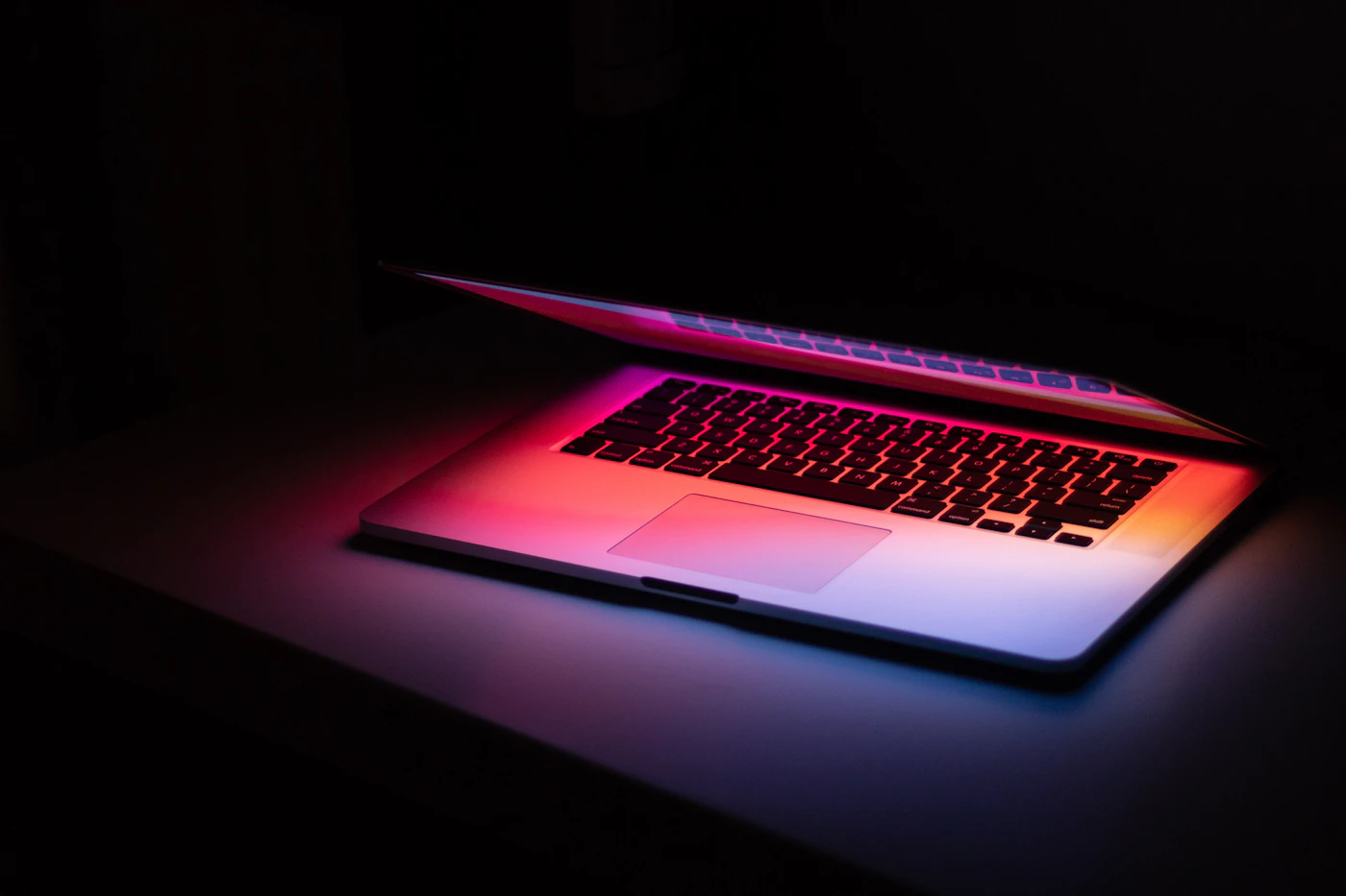 A MacBook on a dark surface, contemplative
