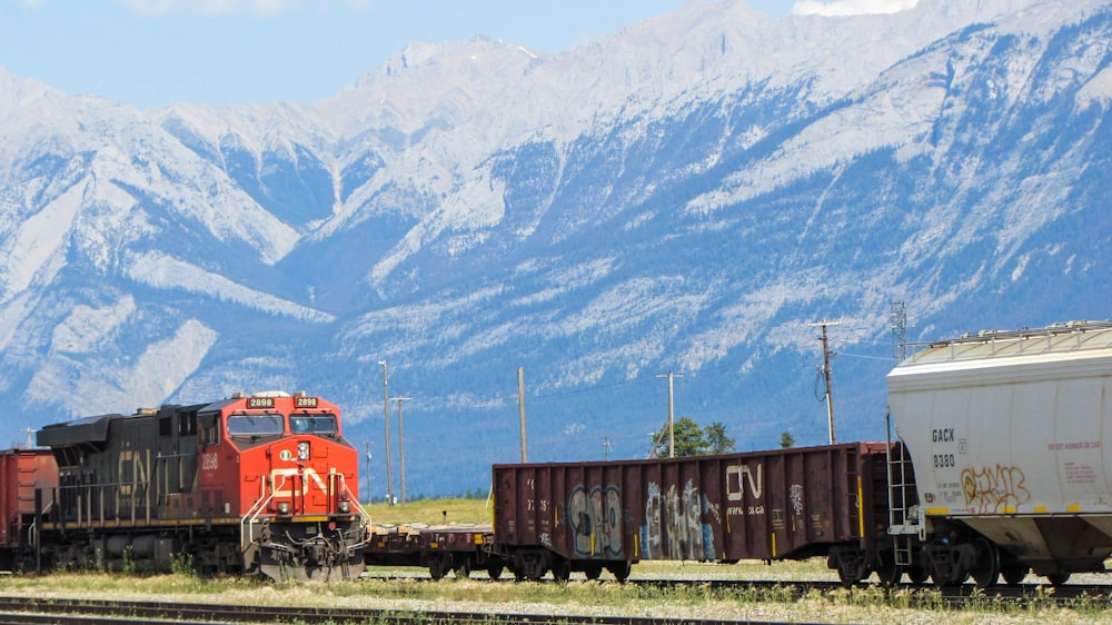 red train on rail road near mountains during daytime