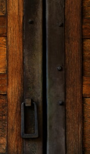 Close-up of a handcrafted rustic wooden door with natural grain and iron handles.