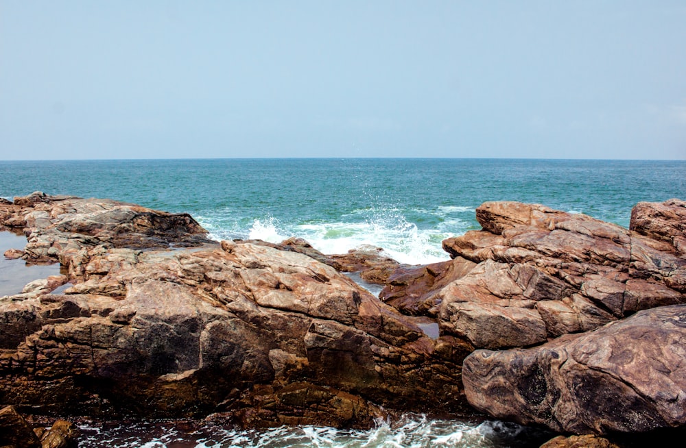 formação rochosa marrom ao lado do mar durante o dia