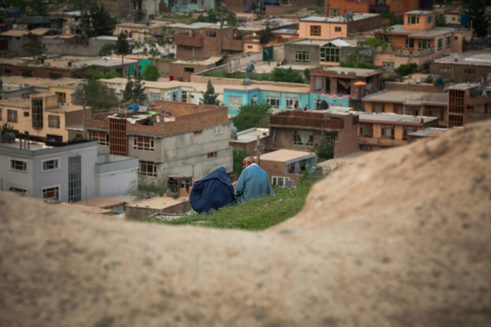 Two people sitting on a hill in Kabul, Afghanistan (Sohaib Ghyasi via Unsplash)