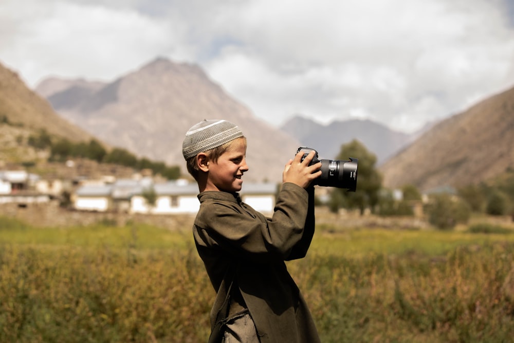 uomo in cappotto nero che tiene la macchina fotografica dslr nera