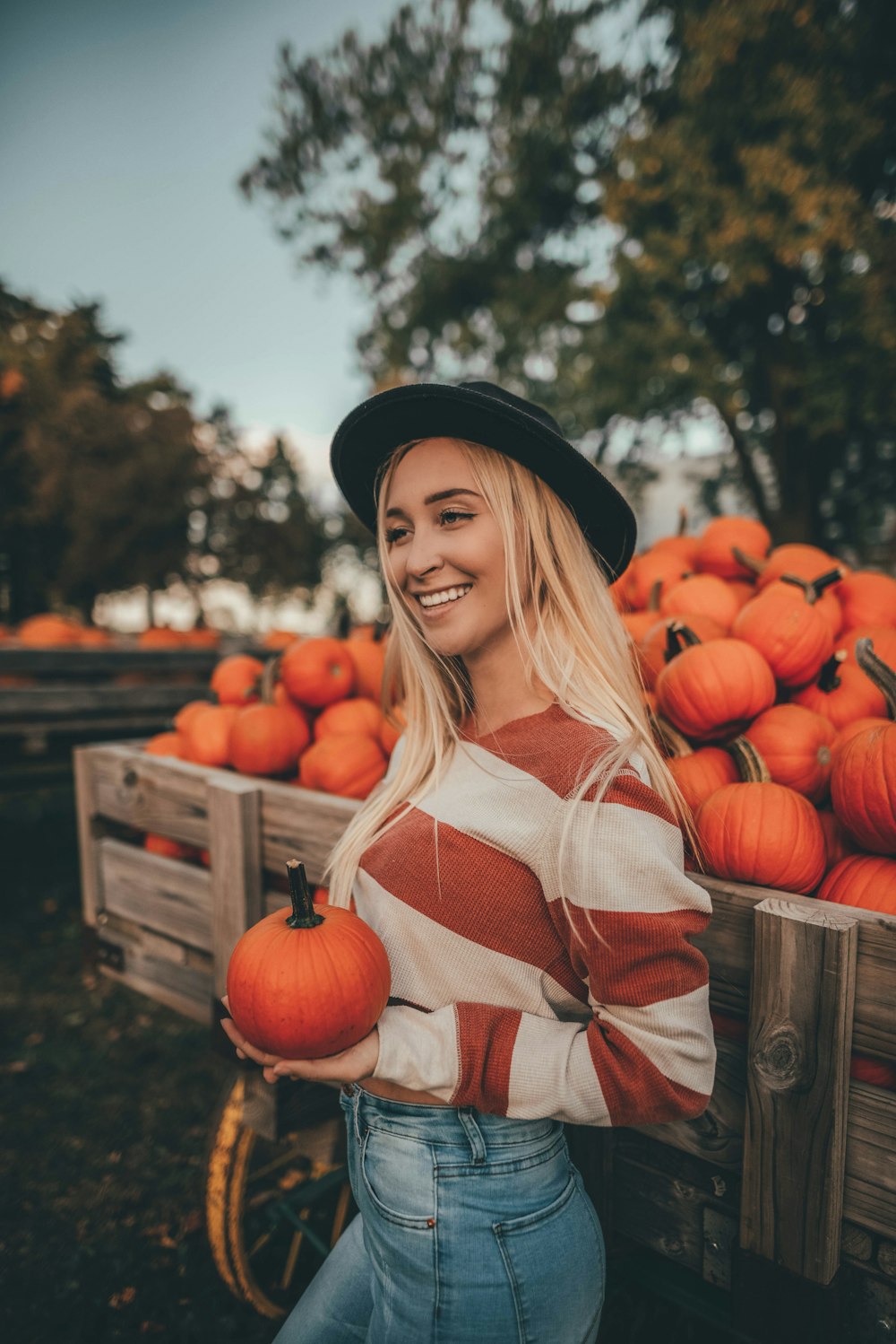 woman in white and red long sleeve shirt holding red pumpkins