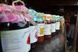 Jars of artisanal fruit jams displayed on a wooden table.