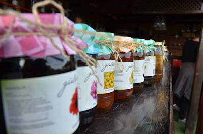 Handcrafted artisanal preserves and jams in glass jars with natural labels on a wooden shelf.