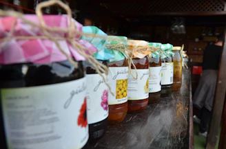 Handcrafted artisanal preserves and jams in glass jars with natural labels on a wooden shelf.