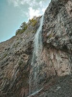 waterfalls on rocky mountain under blue sky during daytime
