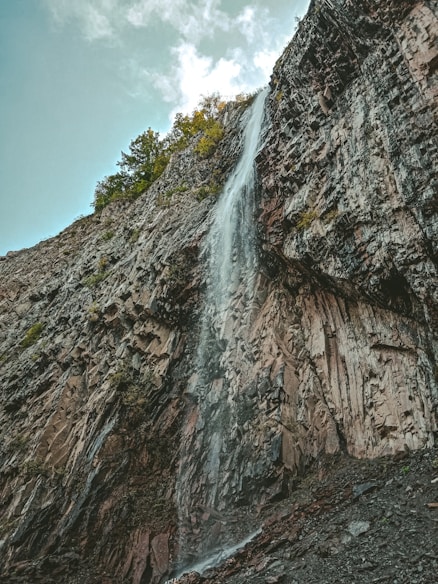 waterfalls on rocky mountain under blue sky during daytime
