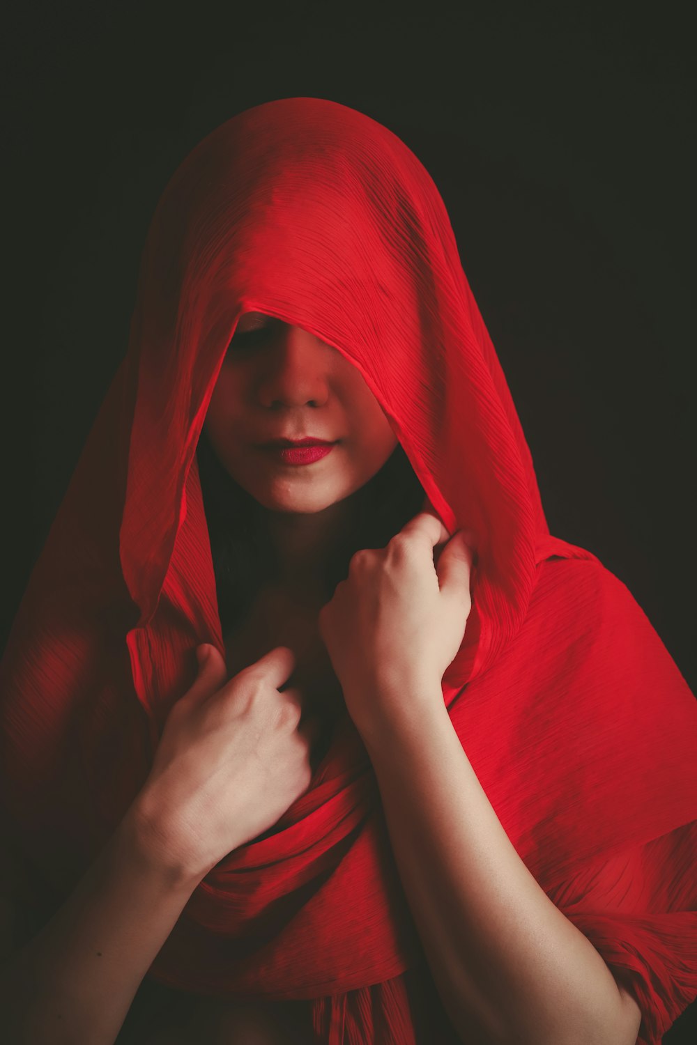 donna che si copre il viso con tessuto rosso