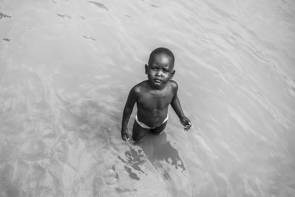 grayscale photo of topless boy on water