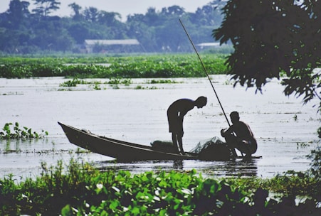 2 men riding on boat on lake during daytime
