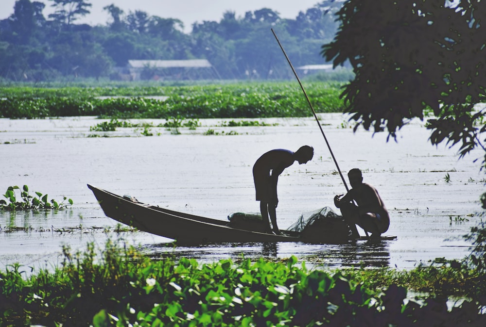 2 men riding on boat on lake during daytime