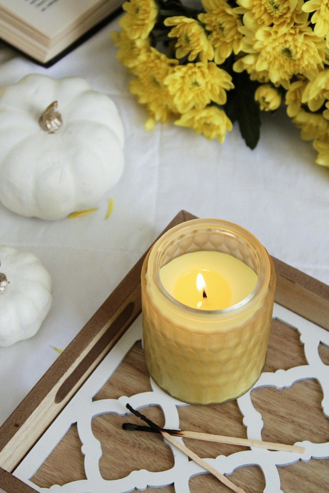 white pillar candle beside yellow flower