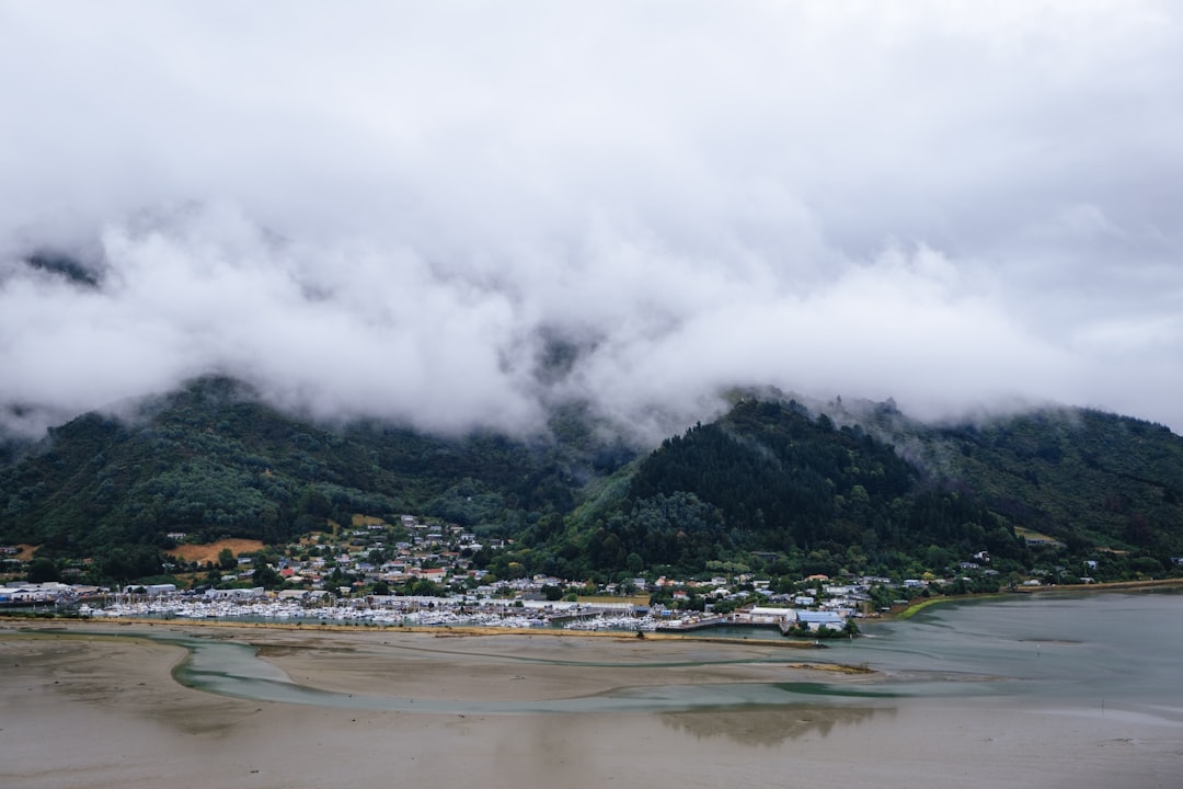 green mountain near body of water under white clouds during daytime