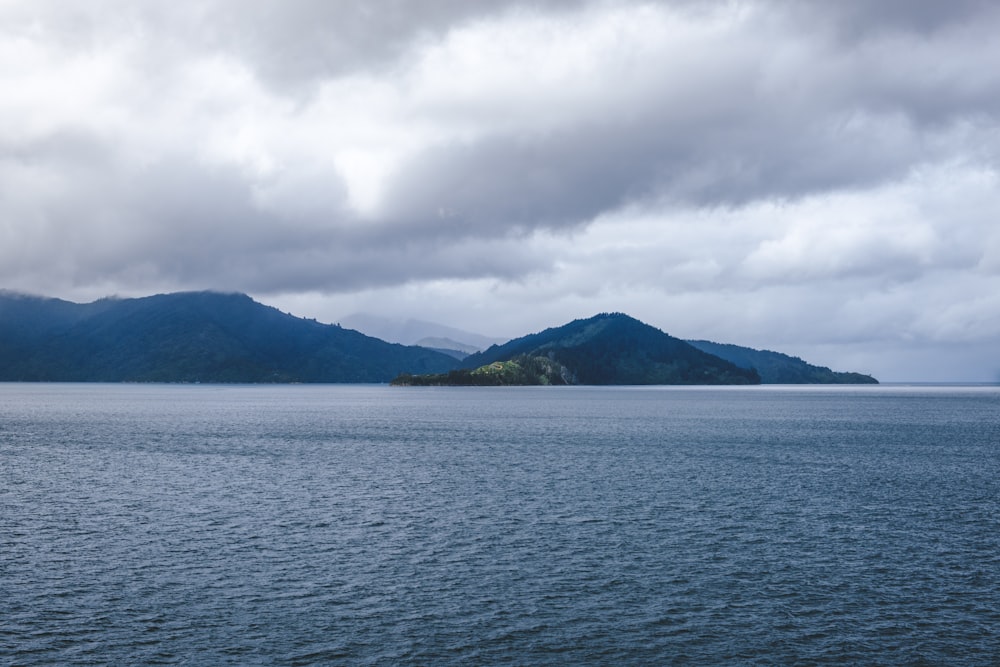 昼間の曇り空の下の山付近の水域