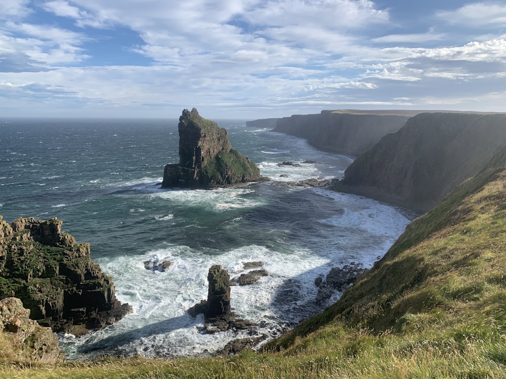 person sitting on rock formation near sea during daytime