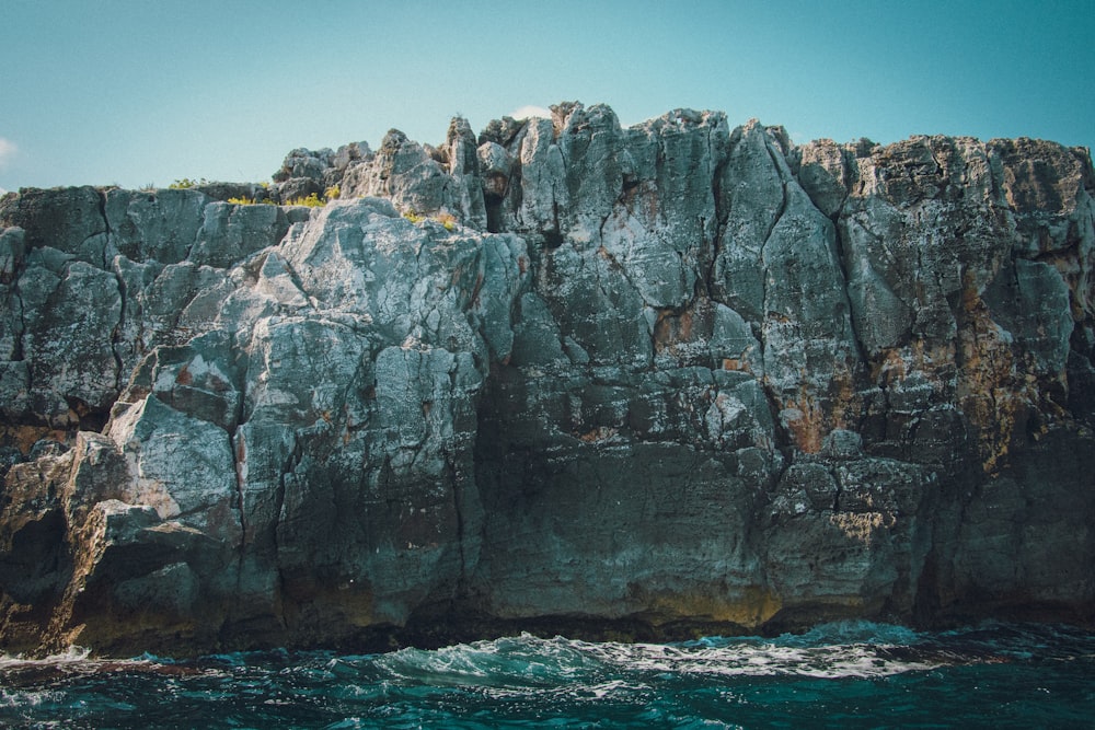 gray rock formation on body of water during daytime