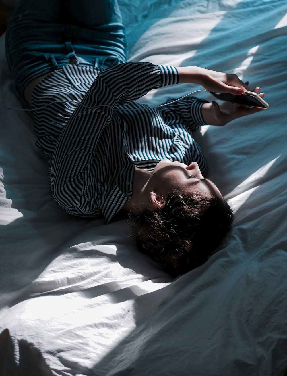 woman in black and white stripe long sleeve shirt lying on bed