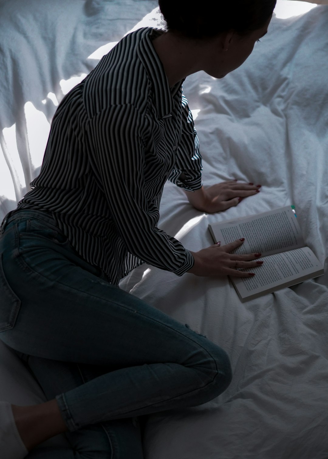 woman in black and white striped shirt and blue denim jeans sitting on bed
