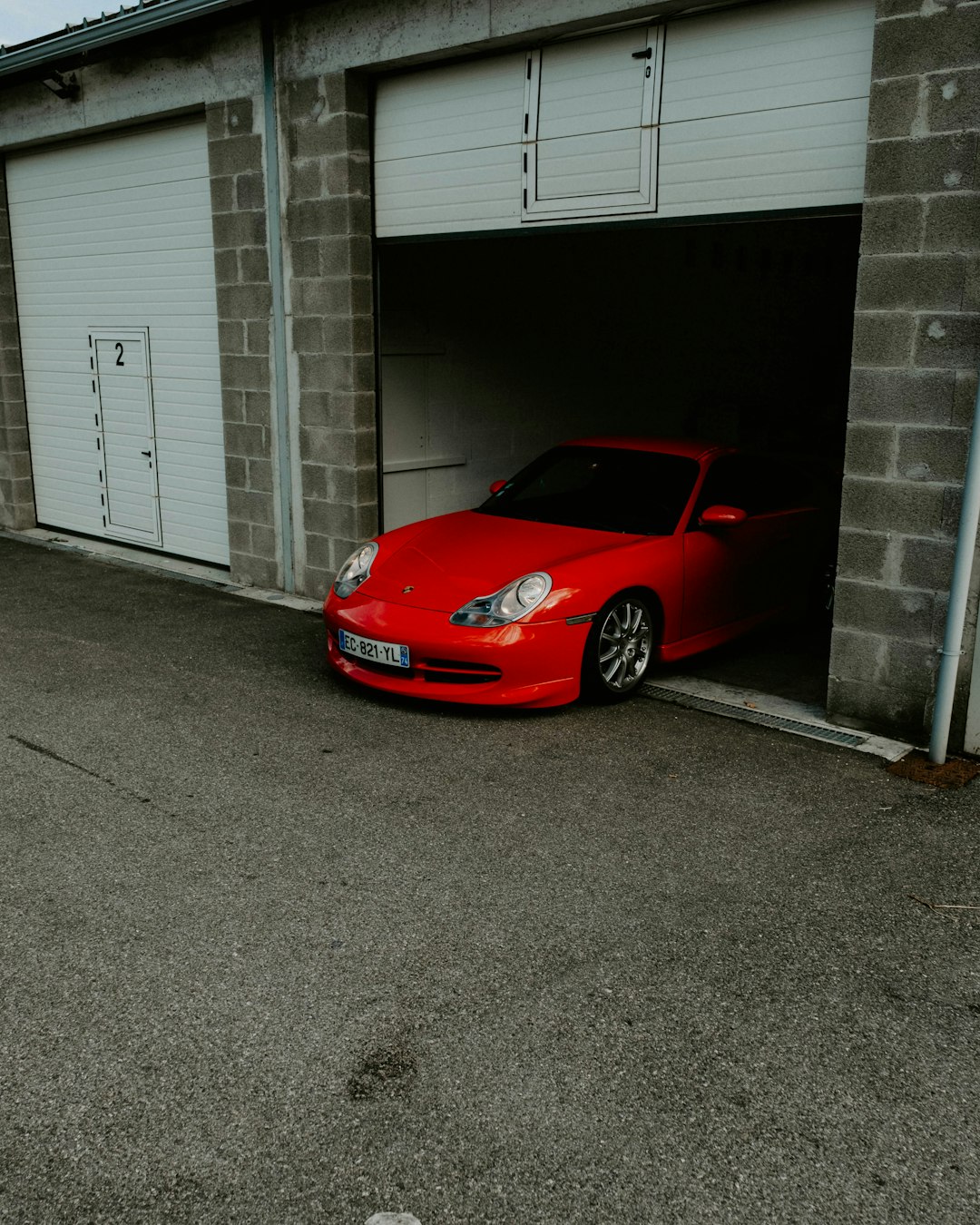red ferrari car parked beside white garage door