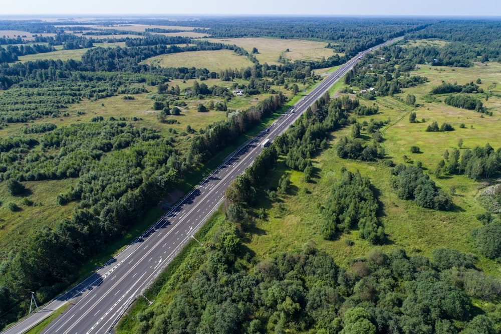 aerial view of highway in between green trees during daytime