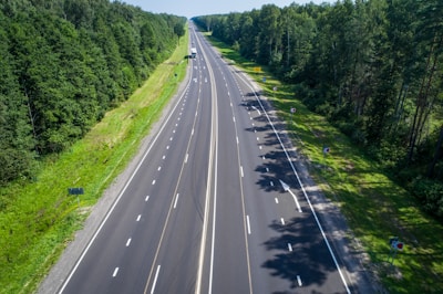 Wide shot of long highway stretching between forests, showing durable road infrastructure.