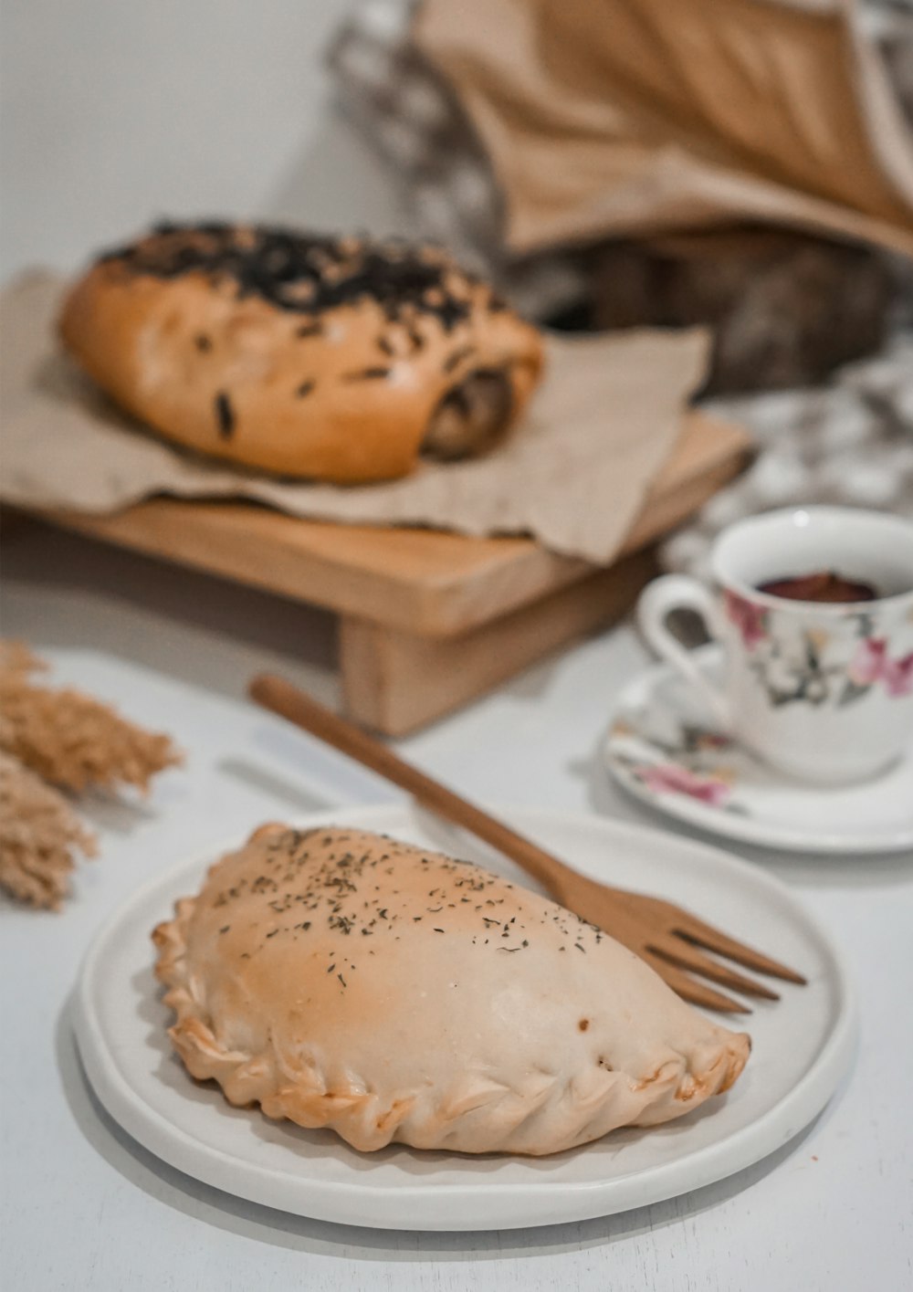 white ceramic teacup on white ceramic saucer beside brown bread
