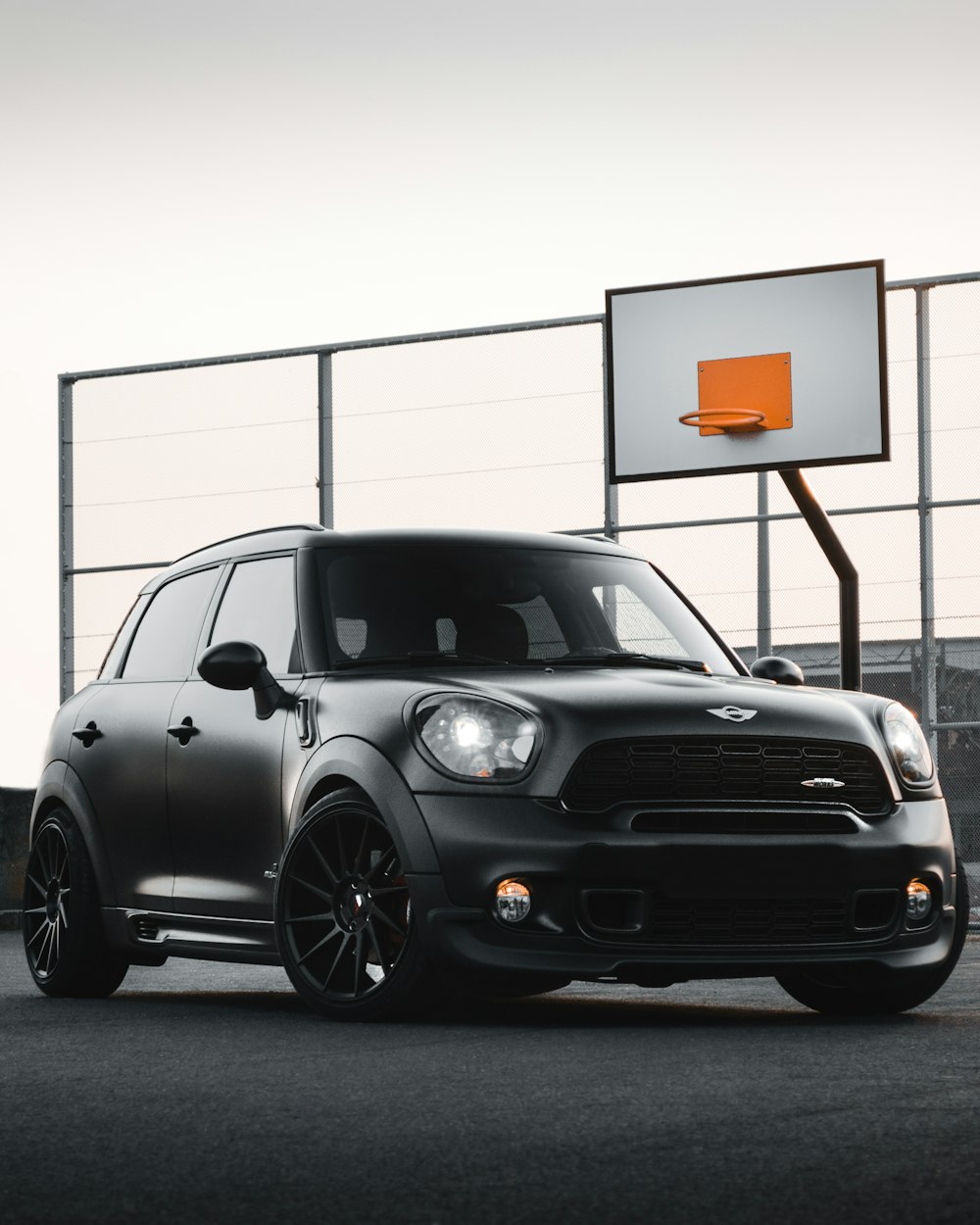 a black mini cooper parked in front of a basketball hoop