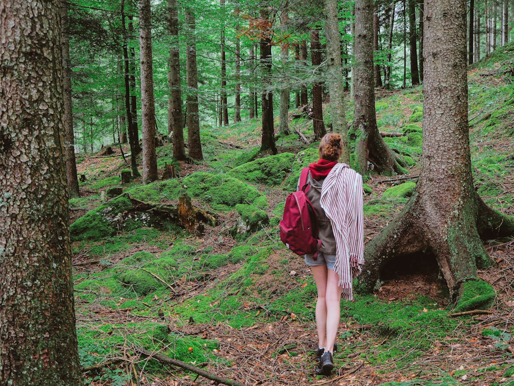 woman in red jacket and white shirt standing in the middle of the woods