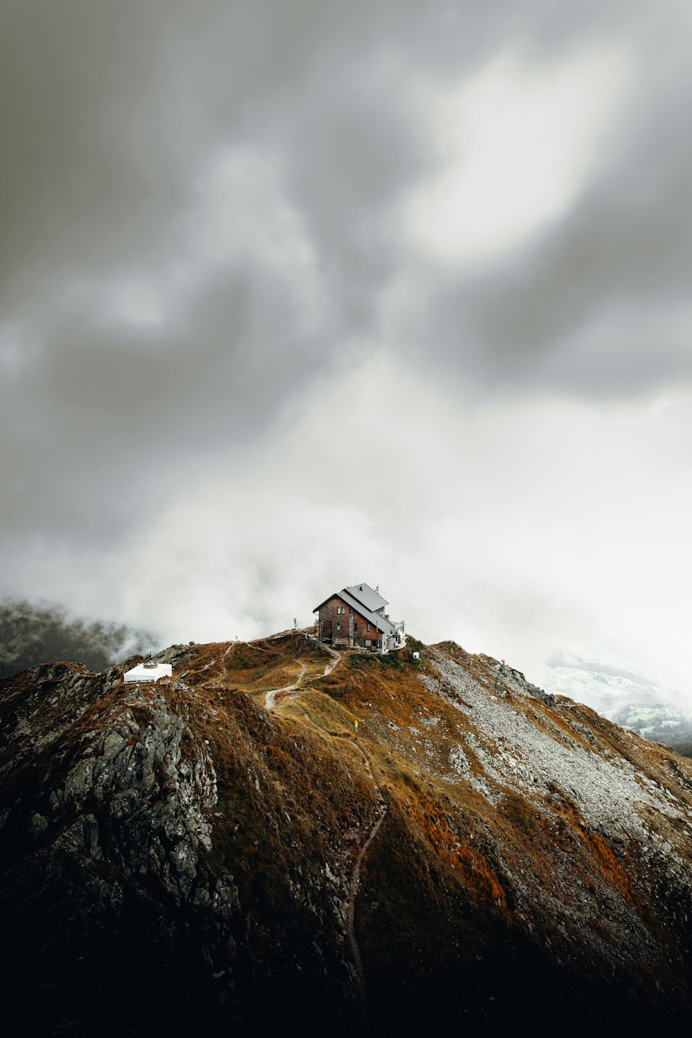 Weißes und braunes Haus auf dem Gipfel des braunen Berges unter weißen Wolken