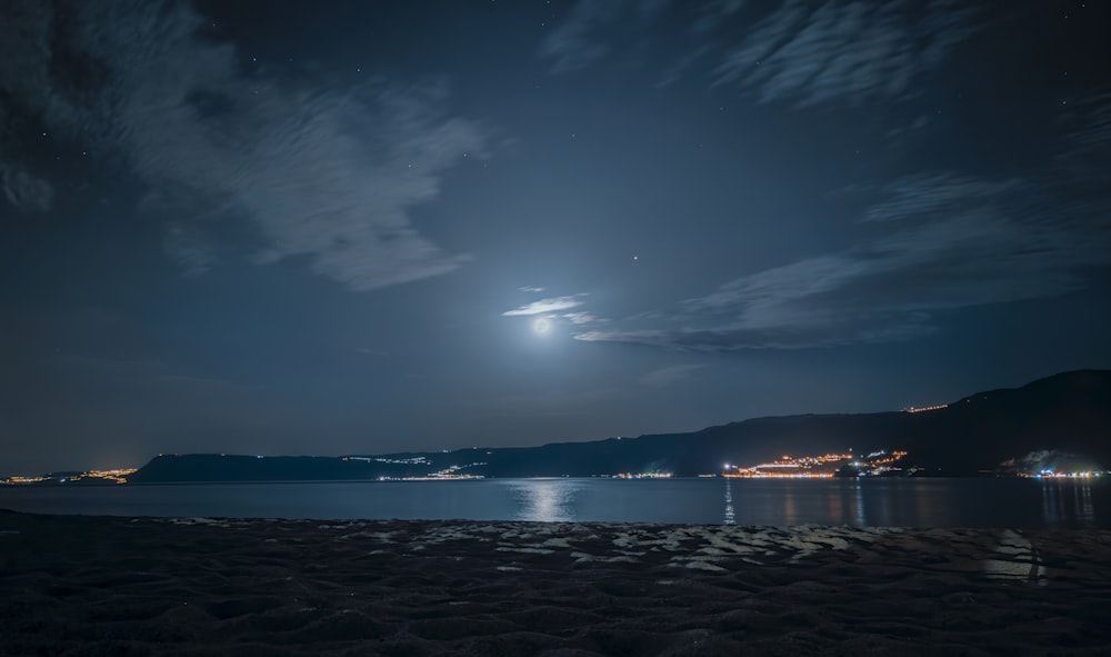 a full moon is seen over a body of water