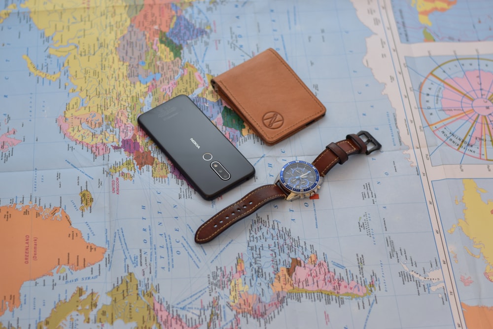 black round analog watch with brown leather strap on white and blue map